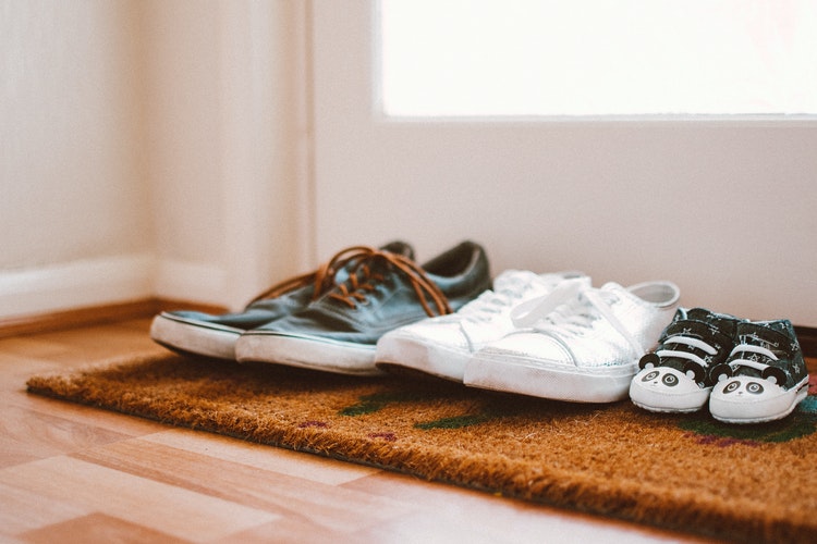 Shoes lined on rug inside entryway of home