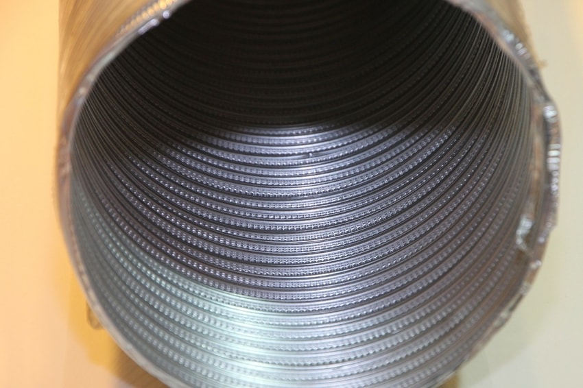 Closeup view of clean aluminum air duct tubing against orange background
