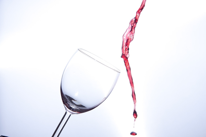 Wine pouring past empty glass onto carpeting below