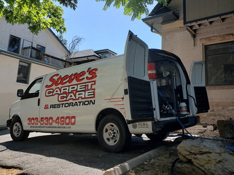 White Steve's Carpet Care &amp;  Restoration work van with truck-mounted cleaning equipment beside Boulder home