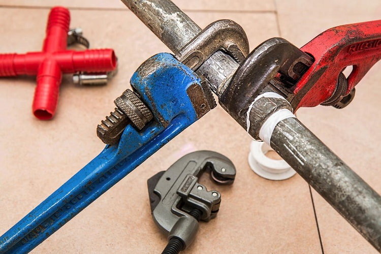 Repair tools tightening water pipe above tiled floor