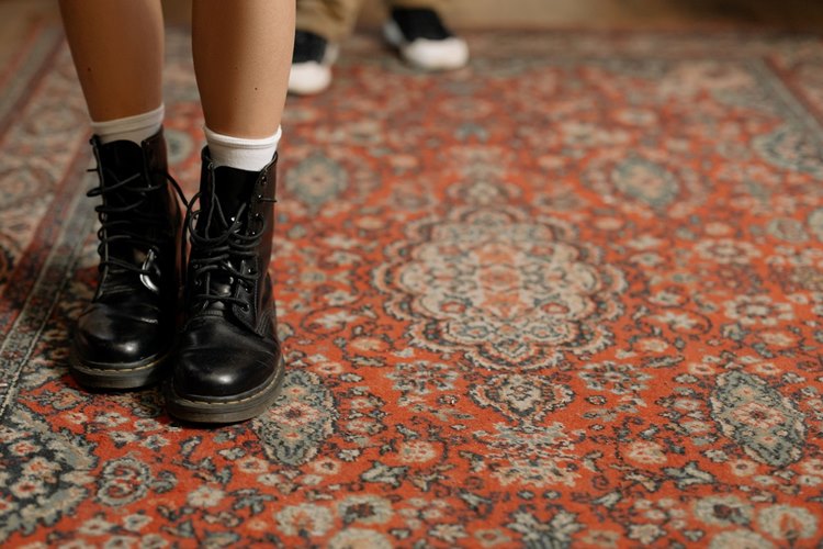 Woman standing on shedding oriental rug in black laced combat boots