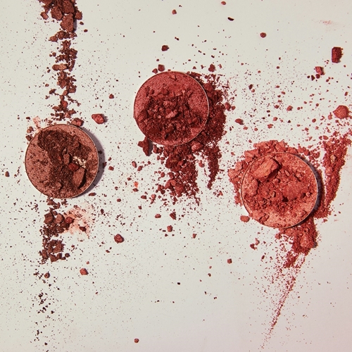 Three powdered blush containers spilling onto white table