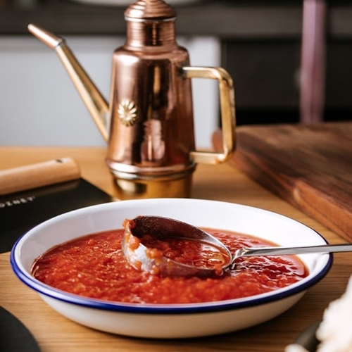 Tomato sauce and stainless steel ladle in wide white bowl