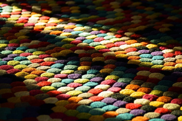 Colorful textured rug in dark room with sunbeams from nearby window