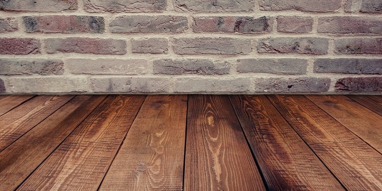 Hardwood flooring in room with exposed brick walls
