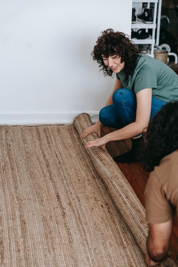 Carpet being unrolled by friends in residential home's living room