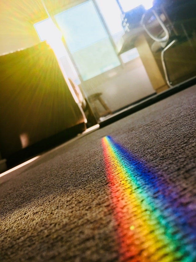 Beige carpeting with rainbow colored line from sunlight through living room window