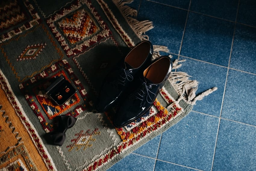 Black dress shoes on a Persian rug with bowtie and cufflinks case