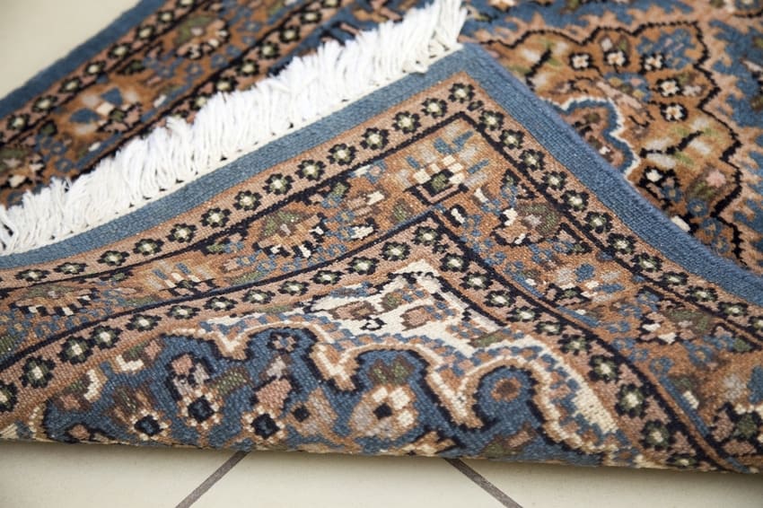Persian rug folded upward to check quality and cleanliness of fibers after professional rug cleaning