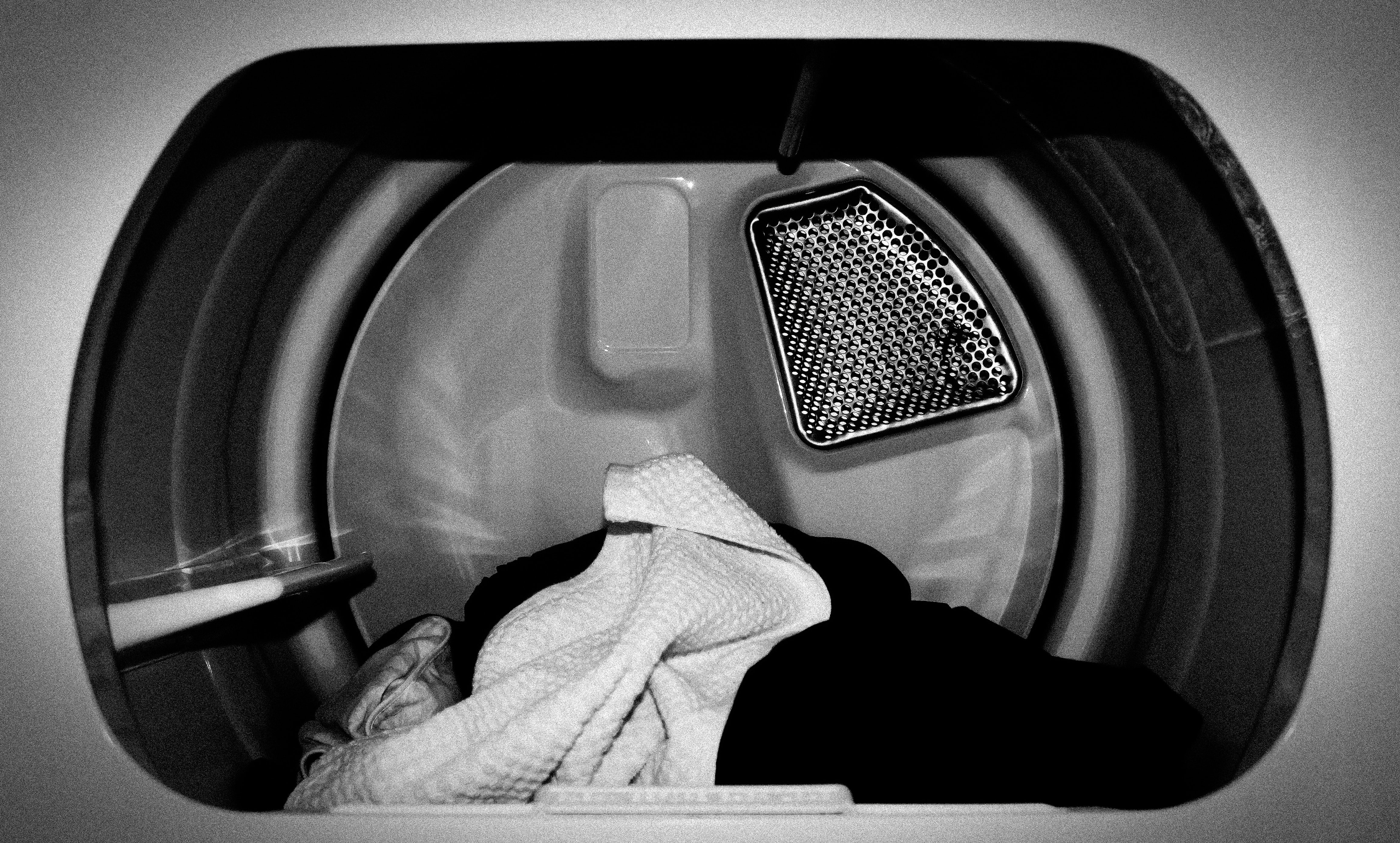 Black and white close-up view of clothes dryer's interior with clothing inside
