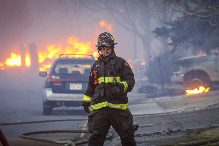 Arvada Fire Department firefighter surrounded by burning homes and smoke during Marshall fire