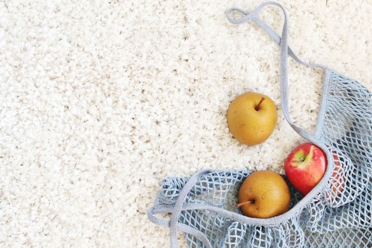 Bag of fruit on white long pile carpet floor