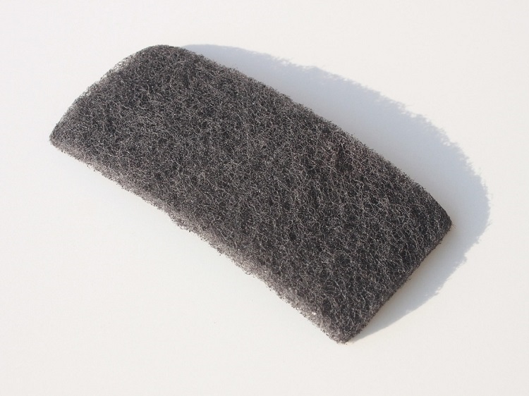Abrasive gray scrubbing pad on while tile surface