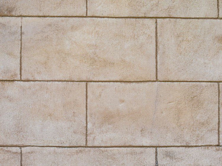 Shower wall covered with large, white tiles and off-white grout