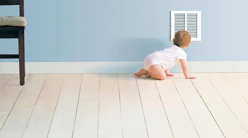 Crawling baby in diaper peering into air duct vent