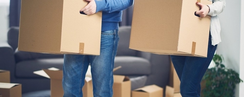 Two people carrying cardboard moving boxes