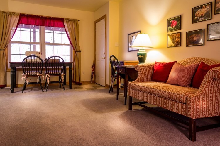 Carpeted room with red and white sofa, lamp, and table with sewing machine