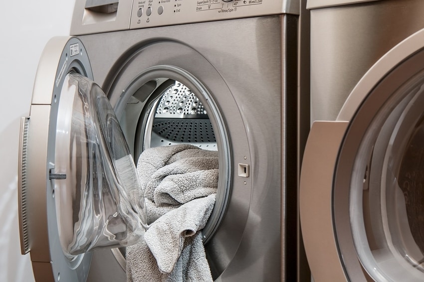 White towel partially protruding from open clothes dryer