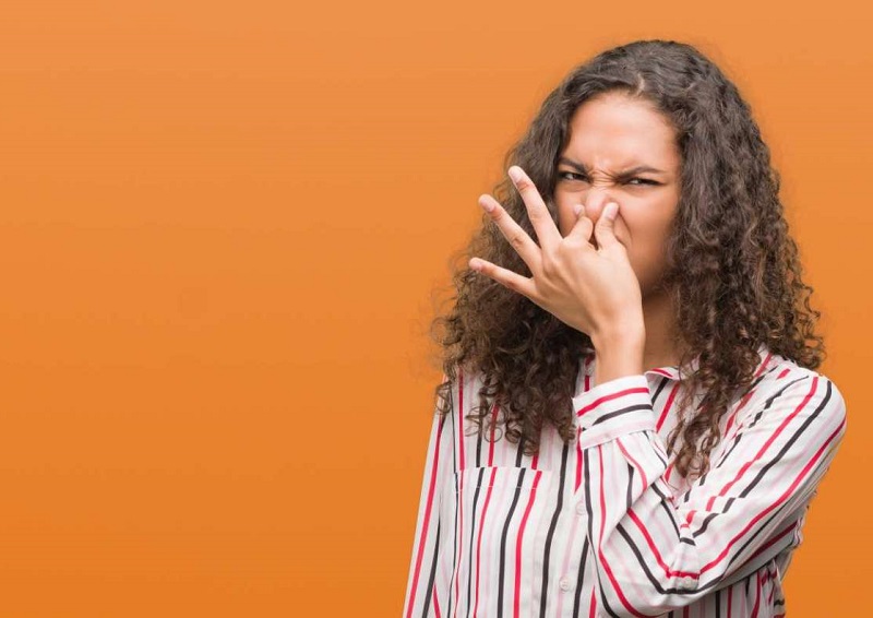 Woman scowling and holding nose because of bad odor