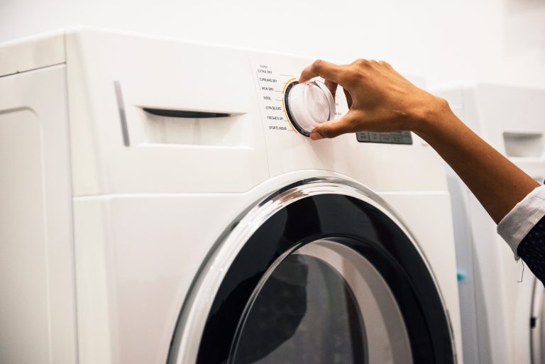 Woman turning nozzle on front-loading clothes dryer
